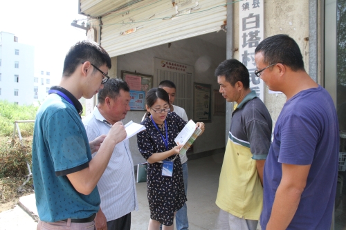 图为该县纪检干部向白塔埠镇村民宣传"指尖"举报方式